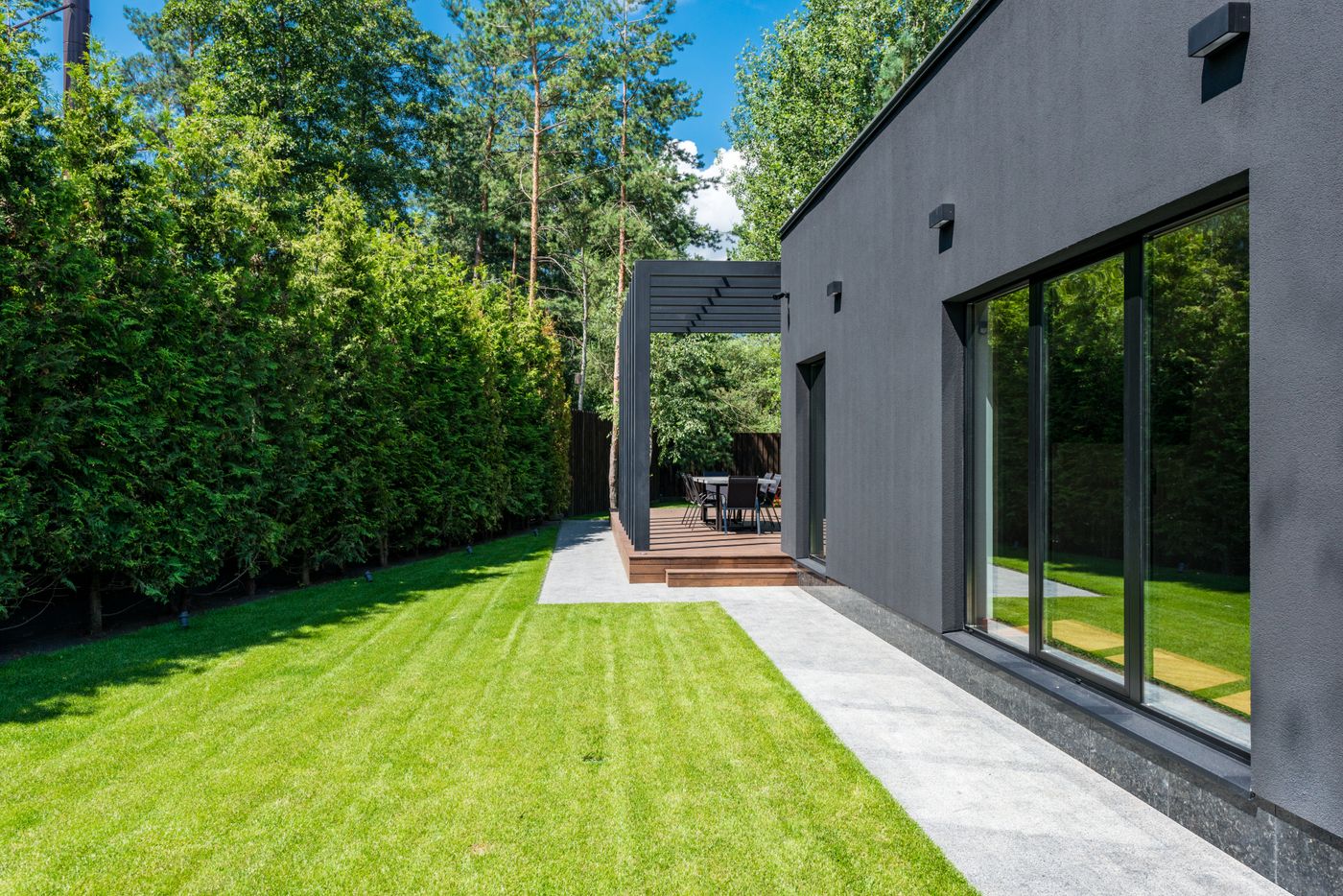 Moderner Garten mit frisch gemähtem Rasen und dichter immergrüner Hecke